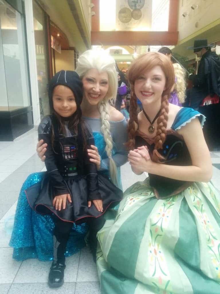 Girl sitting on Ice Queen's lap with Snow Princess at Calgary's Northland Mall Halloween event