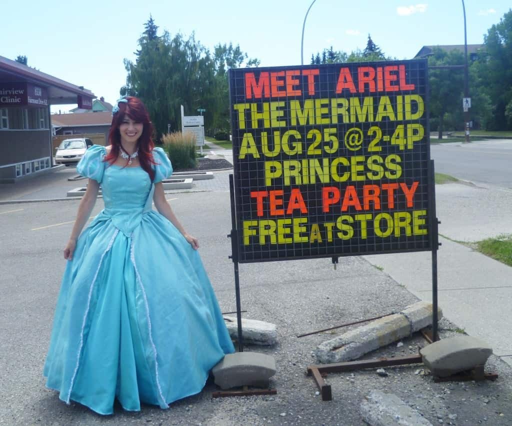 Princess Little Mermaid with Ten Thousand Villages Princess Tea Party Sign outside of Heritage South Calgary Store