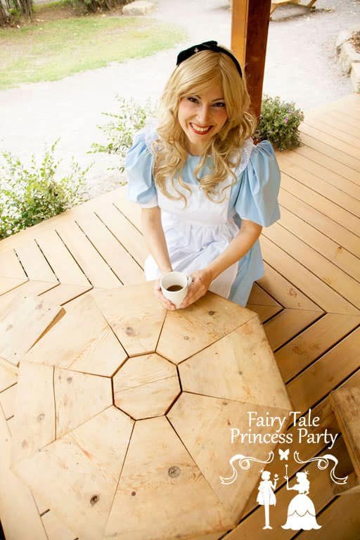 Alice in Wonderland sitting with a cup of tea at a Mad Hatter themed party